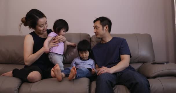 坐在客厅里 坐在沙发上 母亲抱着年幼的女儿 他们的小儿子静静地坐在父亲身边 — 图库视频影像