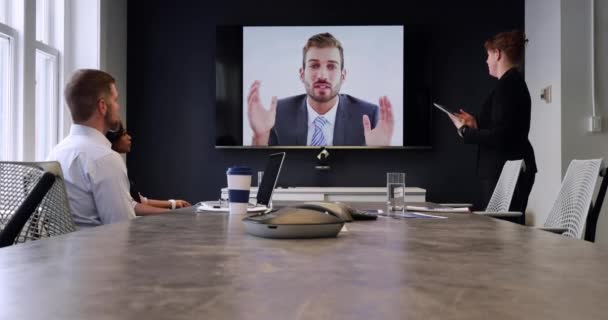 現代のオフィスで働いている男性と女性の白人ビジネスの同僚の背面図 ビデオ会議コール中に会議室のテーブルに座っている女性立っていると男 — ストック動画