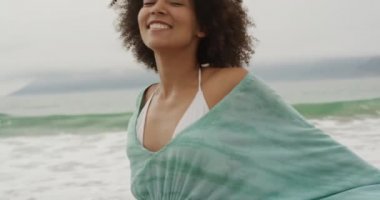 Sahilde neşeyle gülümseyen ve dans eden mutlu Afro-Amerikan bir kadının ön görüntüsü, yavaş çekim.