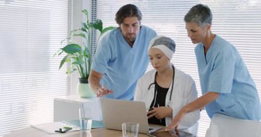 Kafkasyalı erkek ve kadın bir sağlık çalışanının önlük giyip, laboratuvar önlüğü giyen, melez bir kadın sağlık görevlisinin her iki tarafında durduğu ön manzara. 