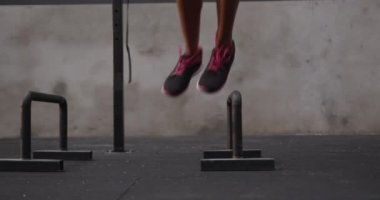 Atletik melez bir kadının düşük seviyeli antremanı. Spor salonunda hoplayıp zıplıyor.