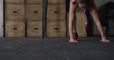 Spor kıyafetleri içinde spor kıyafetleri giymiş, spor salonunda çapraz antrenman yapan, burpee yapmak için aşağıya inen, ayağa kalkıp koşan, ağır çekim