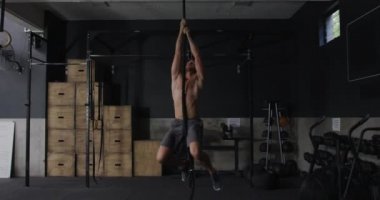Spor salonunda antrenman yapan üstsüz, beyaz bir adamın ön görüntüsü. Yavaş çekimde barfiks çekiyor.