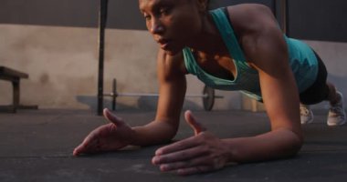 Spor kıyafetleri giymiş, spor kıyafetleri giymiş spor salonunda antrenman yapan, tahta pozisyonunda ağır çekimde spor yapan bir kadının ön görüntüsü.