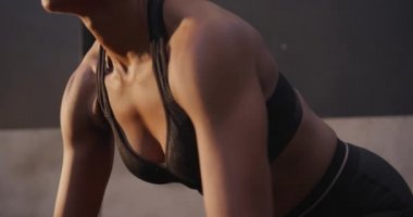 Spor kıyafetleri giyen, spor salonunda çapraz antrenman yapan, öne eğilip ağırlık kaldıran ve ağırlık kaldıran bir kadının yan görüntüsü.