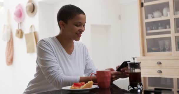 Вид Сбоку Афроамериканки Дома Кухне Сидящей Завтраком Кофе Пользующейся Смартфоном — стоковое видео