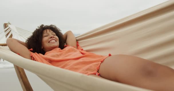アフリカ系アメリカ人女性の海沿いのビーチの正面の景色は ハンモックの笑顔で スローモーションに横たわっている — ストック動画