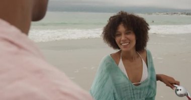 Sahilde bisiklet tutan ve konuşan Afrikalı Amerikalı bir çiftin omuzlarının üstünden.