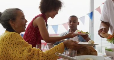 Afrika kökenli Amerikalı bir kadın ve son sınıf öğrencisinin ayakta durup ailelerine hizmet ederken, yemek masasında oturup kutlama yaparken, ağır çekimde...