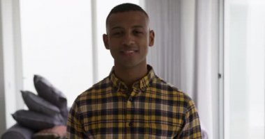 Yeni evinin oturma odasında gülümseyen Afro-Amerikan bir adamın portresi. Arka planda yastık yığınları, yavaş çekim.