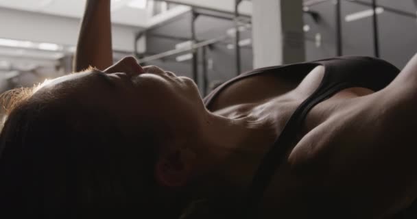 一名身穿运动服的白人女运动员躺在体操台上 吊起哑铃 慢动作 侧视近视 — 图库视频影像
