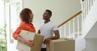 Afrika kökenli Amerikalı bir çiftin, yeni evlerinin koridorundaki bir yığın kutunun yanında durduğu, bir an için dinlenen, etrafa bakıp gülümseyen, ağır çekim