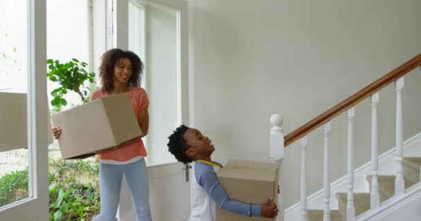 彼らの若い娘が待っている新しい家の廊下に段ボール箱を持っているアフリカ系アメリカ人の家族と彼らの若い息子の側面図 スローモーション — ストック動画