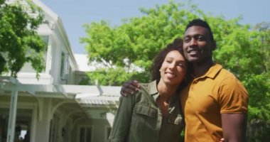 Bahçede gülümseyen, güneşe sarılan ve kameraya gülümseyen Afrikalı Amerikalı bir çiftin portresi.