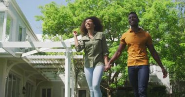 Gülümseyen Afro-Amerikan bir çiftin el ele tutuşup güneşte gülümsemesinin alçak açılı görüntüsü.