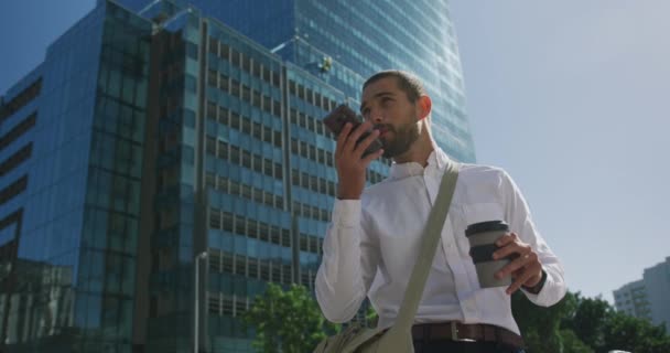 도시에 사업가의 스마트폰으로 얘기하고 사무실 건물느린 움직임 테이크 — 비디오