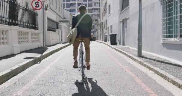 街の外出先で若い白人ビジネスマンのリアビュー 路上で自転車に乗って スローモーション — ストック動画