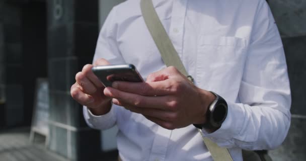 一个年轻的白种人商人在城市里走来走去 在街上用智能手机发短信 慢动作 — 图库视频影像