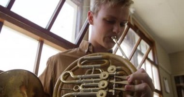 Ön cephede, biri Fransız kornosu çalan diğeri de ağır çekimde trombon çalan iki Kafkasyalı genç müzisyenin provası var.