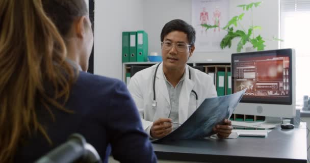 Через Плече Пацієнтка Сидить Столом Слухає Азіатський Лікар Говорить Вказує — стокове відео
