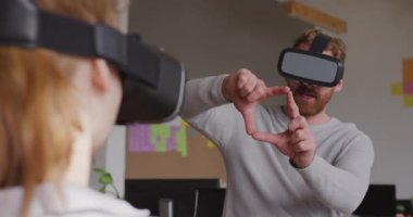 Modern bir ofiste, VR kulaklıklar takmış, VR kulaklık takmış, VR kulaklıklı, kadın meslektaşının arka görüşüyle sanal interaktif ekrana dokunan, yaratıcı genç bir adamın ön görüntüsü.