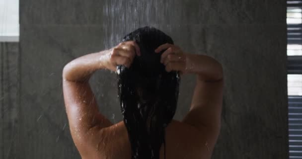 在后视镜下 一位白种人年轻女子 一头乌黑的长发 站在现代浴室的淋浴下 挽着她的头发 慢动作 — 图库视频影像