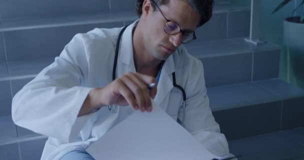 Вид Белого Врача Больнице Очках Халате Стетоскопе Сидящего Лестнице Пишущего — стоковое видео