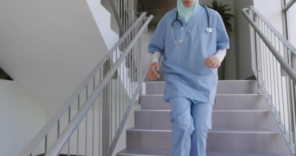 病院の階段を駆け下りスローモーションのハイジャブを身に着けている混合レースの女性医療従事者の正面図 — ストック動画