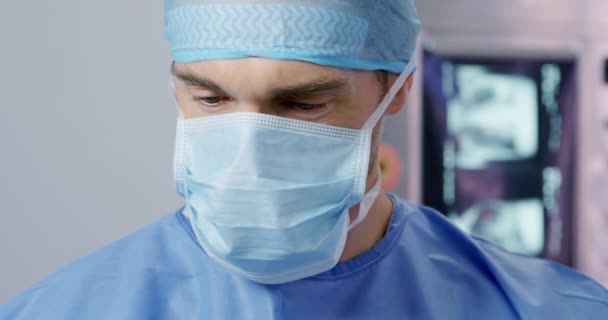 手術用キャップとマスクを身に着けている病院の手術室で働く白人男性医療専門家の最前線ビューを見下ろします 背景に医療機器と — ストック動画