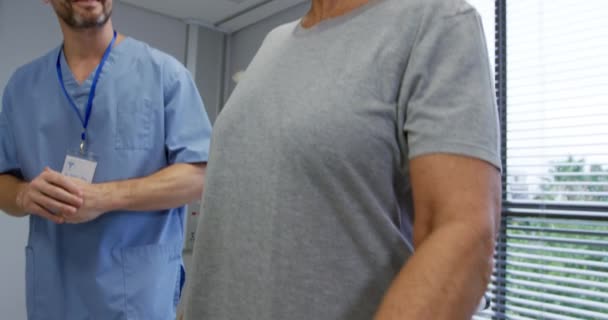 白人男性理学療法士のサイドビュー病院での理学療法セッション中に平行棒の間に義肢歩行を持つ白人女性患者を助ける スローモーション — ストック動画