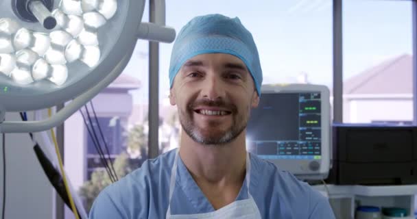 在医院手术室里 一位头戴外科帽 头戴刷子 头戴外科帽 站在医院手术室里 面带微笑地对着摄像机的白俄罗斯男性医护人员的画像 — 图库视频影像