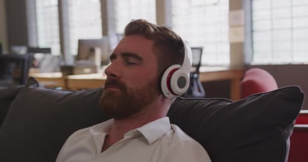 Modern Bir Ofiste Bir Koltukta Oturmuş Kulaklıkla Müzik Dinleyen Ağır — Stok video