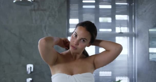 在现代浴室里 一位身穿浴巾的白人年轻女子在刷洗她长长的黑发 — 图库视频影像