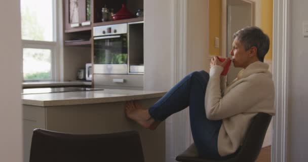 Evde Mutfağında Kısa Gri Saçları Olan Dizleri Yukarıda Ayakları Yukarıda — Stok video
