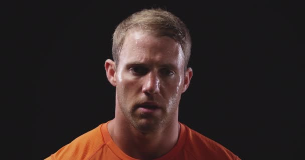 一个白种人男子 穿着橙色T恤衫 在练习后汗流浃背 动作缓慢 背景是黑色的 — 图库视频影像