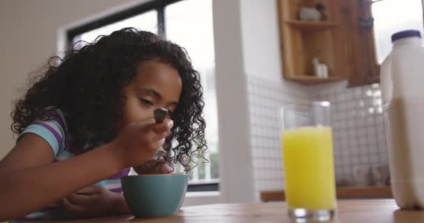 彼女の前のテーブルの上にオレンジジュースのガラスで 朝食のシリアルのボウルを食べてテーブルに座って ゆっくりと動き — ストック動画