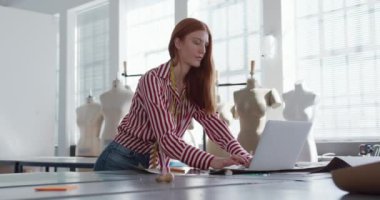 Moda okulundaki bir stüdyoda bilgisayar üzerinde çalışan beyaz ırktan genç bir kız öğrencinin ön görüntüsü.