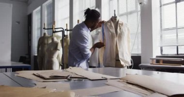 Moda okulundaki bir stüdyoda tasarım üzerinde çalışan Afro-Amerikalı genç bir erkek moda öğrencisinin ön görüntüsü.