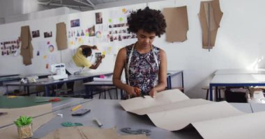 Moda okulunda bir tasarım stüdyosunda çalışan Afrika kökenli beyaz ırktan genç bir kadın moda öğrencisinin ön görüntüsü.