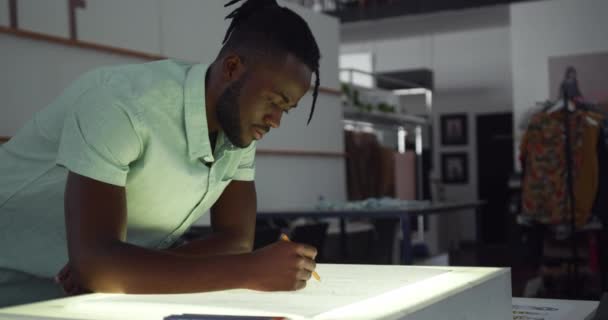 ファッション大学のスタジオでデザインに取り組む若いアフリカ系アメリカ人男性ファッション学生のフロントビュー — ストック動画