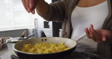 Karışık ırktan bir kadının evde eğlenmesi, mutfakta kahvaltı hazırlaması, yağda yumurtaya tuz eklenmesi, ağır çekim.