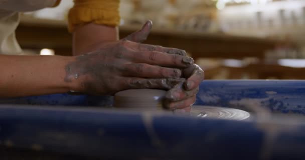 一个年轻的白种人女陶工坐在陶工轮旁 转动着一块粘土 用手在一个陶器工作室里塑造它 动作缓慢的侧面视图 — 图库视频影像