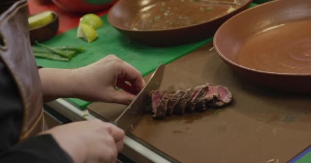 一个白人女厨师在一个繁忙的餐馆厨房里工作 把肉切成薄片 放在盘子里的高角形侧视图 — 图库视频影像