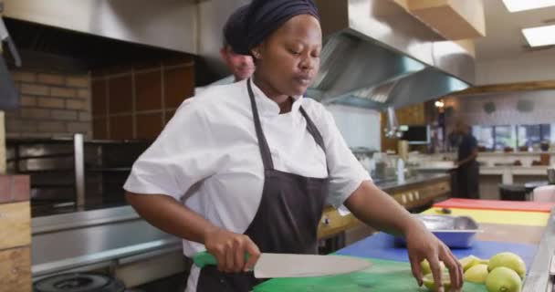 厨房里一位白人男性餐厅经理的照片 手里拿着一个剪贴板 与一位非裔美国女厨师交谈 发出指示 — 图库视频影像