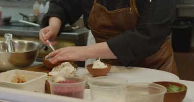 Yoğun bir lokanta mutfağında çalışan beyaz bir kadın aşçının ön tarafı. Baharatlı yemekler hazırlıyor. Arka planda çalışan meslektaşları.