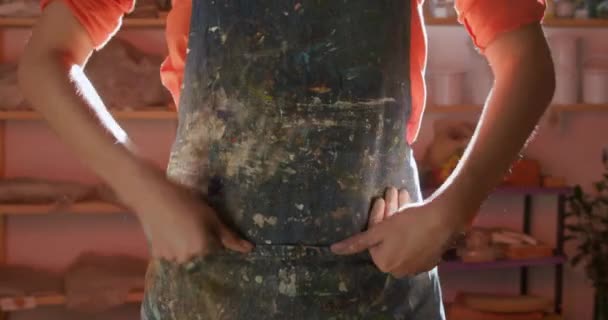 一位年轻的白种人女陶工站在一个陶瓷工作室里 在围裙上洗手 — 图库视频影像