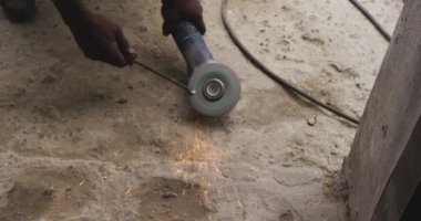Kasaba atölyesinde bir Afrika erkek atölyesinin ön görüntüsü, bir tel çekmek için açı öğütücü kullanıyor, yavaş çekim.