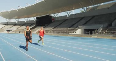 Kafkas ve karışık ırk erkek sporcularının spor stadyumunda antrenman yaparken, koşu pistinde birbirleriyle yarışırken, yavaş çekimde.