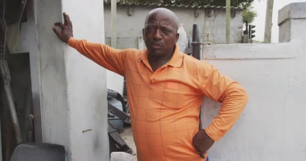 Portret Afrykanina Obok Warsztatu Mieszczańskiego Ubrany Pomarańczową Koszulę Opierający Się — Wideo stockowe