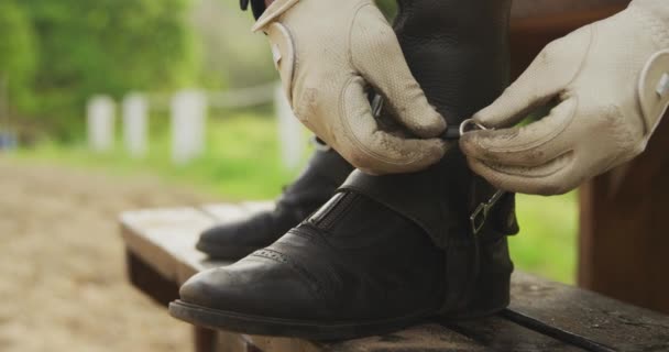 一个穿着漂亮的男性骑手戴着手套 脚踏在长椅上 在骑马前调整马靴上的马刺 动作缓慢的低部分侧视图 — 图库视频影像